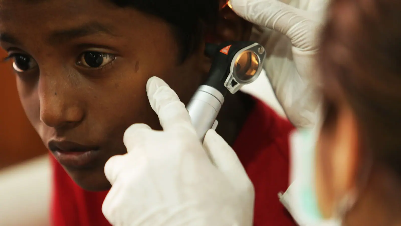 Clinician examining a young boy’s ear with an otoscope